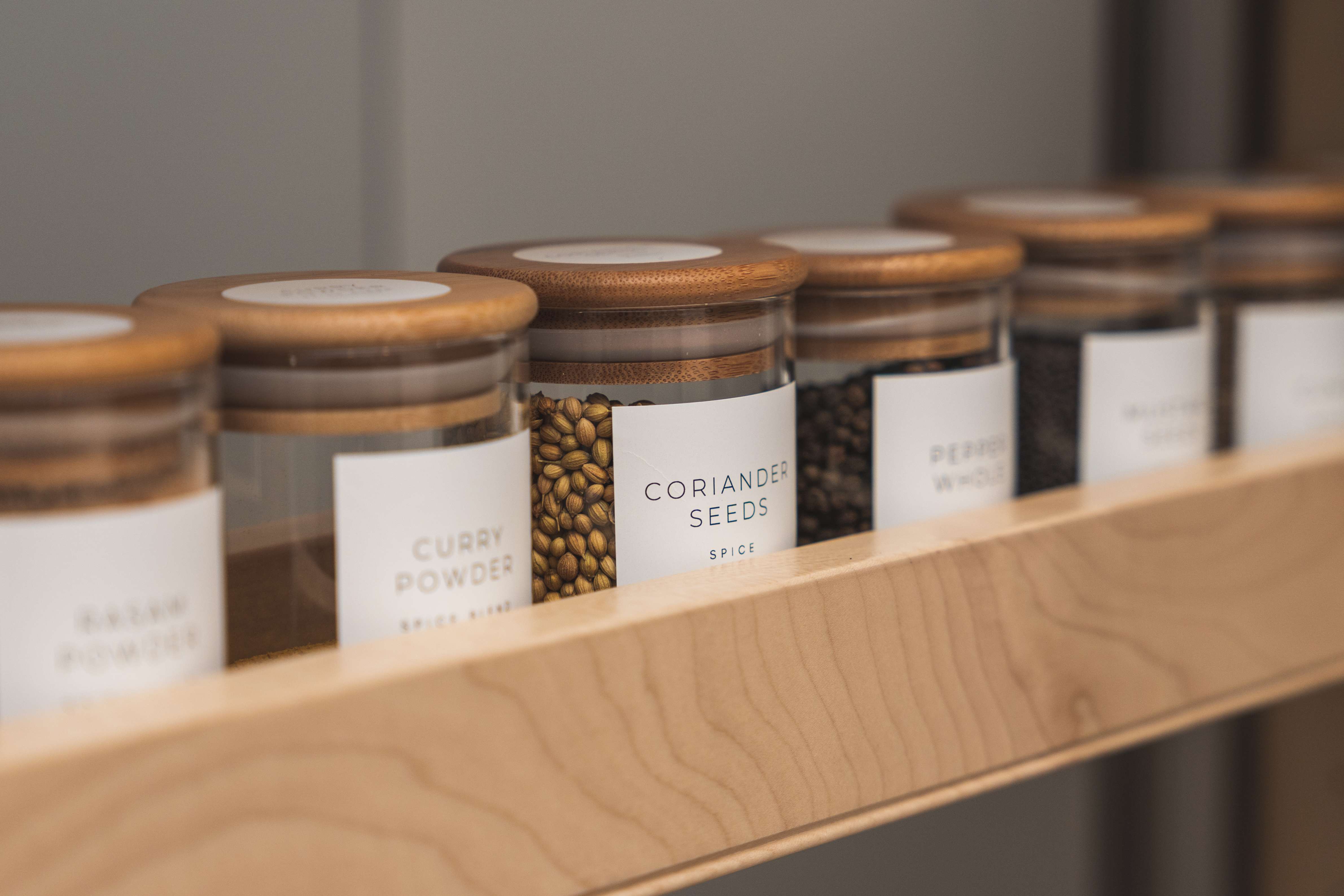 Neatly organized spice jars labeled 'CURRY POWDER', 'CORIANDER SEEDS', etc.